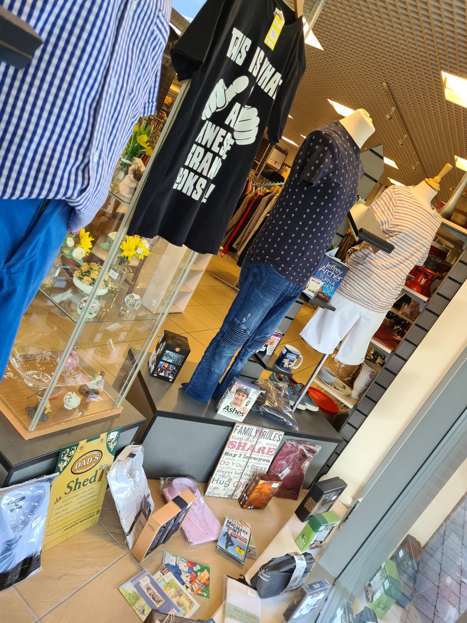 This shows a shop window with a Father's Day display put together by Alison. There's four mannequins all wearing mens clothing and other gifts on the floor including mugs, dvds and dad's shed signs. 