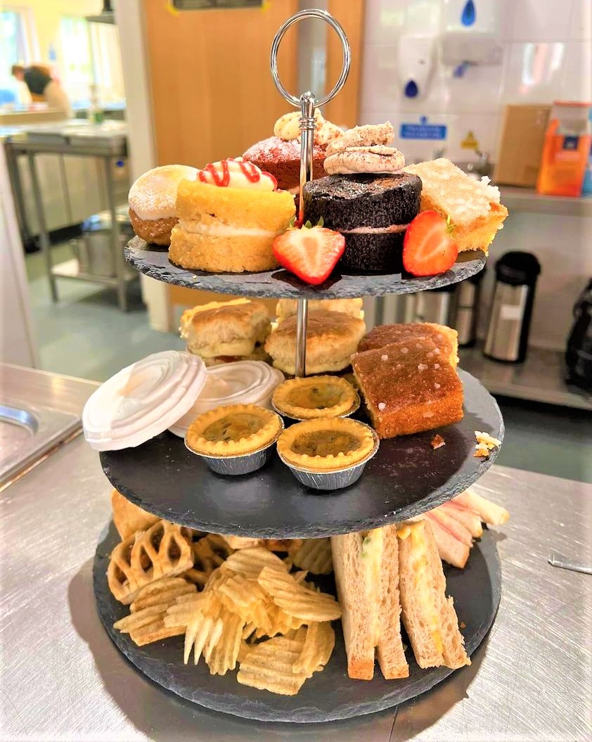 This image shows one of our Afternoon teas, on the bottom row is savoury items with sweet treats including cakes, meringues and strawberries on the top two rows.